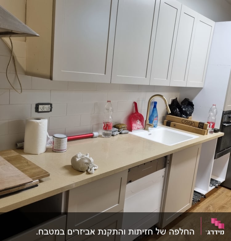 מטבח עם ארונות לבנים, כיור וברז זהב